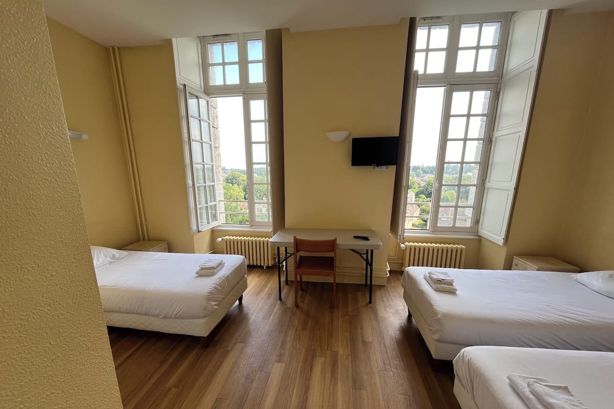 A room with two beds, a desk, a chair, and a TV.