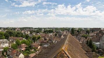 A cityscape with a prominent historical building featuring a steep, sloped roof.
