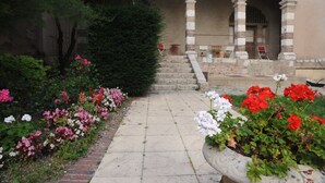 A garden pathway leading to a building with arches and a brick wall. - Hotellerie Saint Yves (Chartres)
