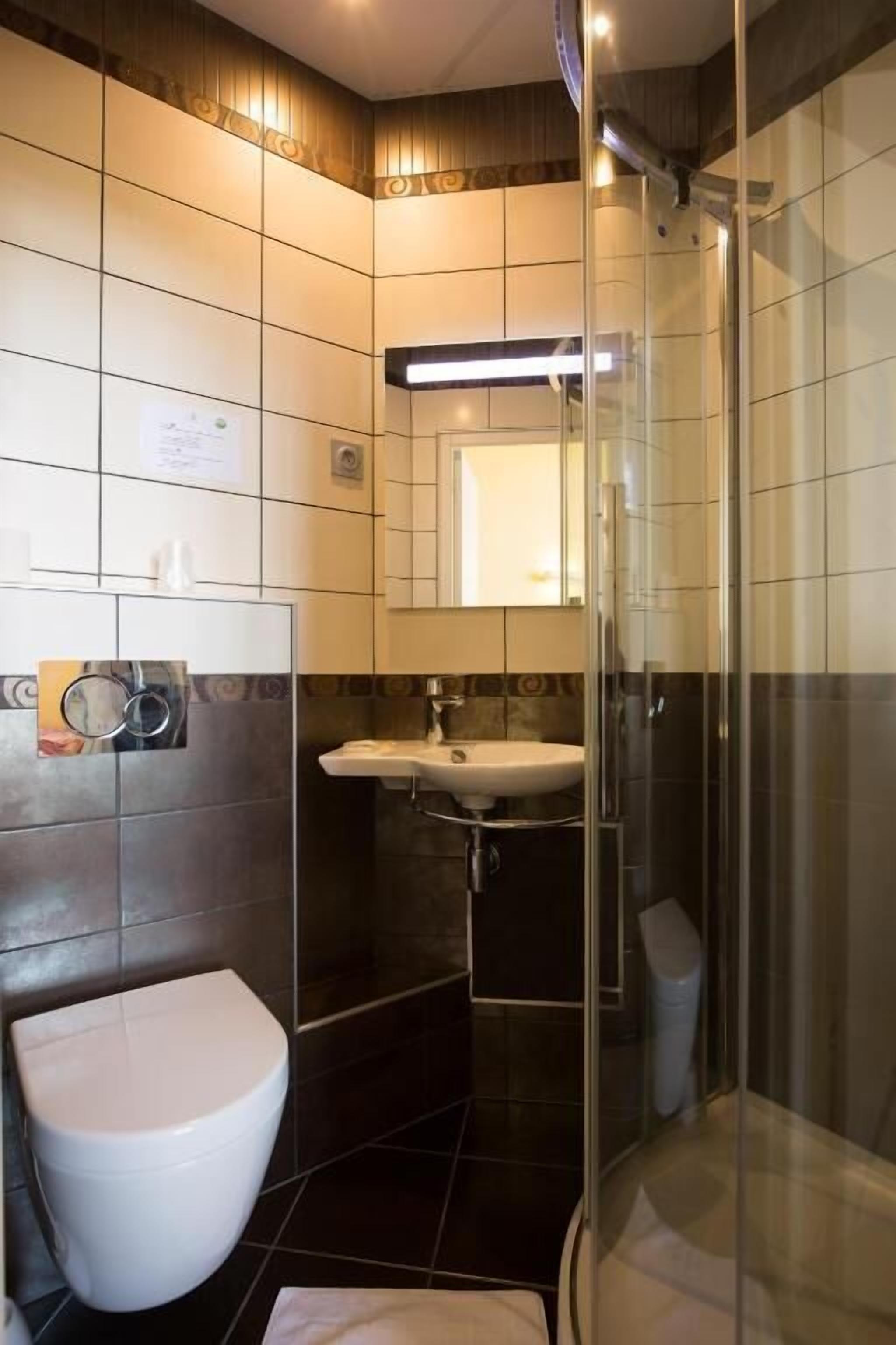 A modern bathroom with a glass-enclosed shower, a white toilet, and a sink with a mirror above it.