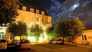 A historic building with a large dome and multiple windows, surrounded by trees and parked cars. - Hotellerie Saint Yves (Chartres)