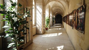 A corridor with arched ceilings, potted plants, and artwork on the walls. - Hotellerie Saint Yves (Chartres)