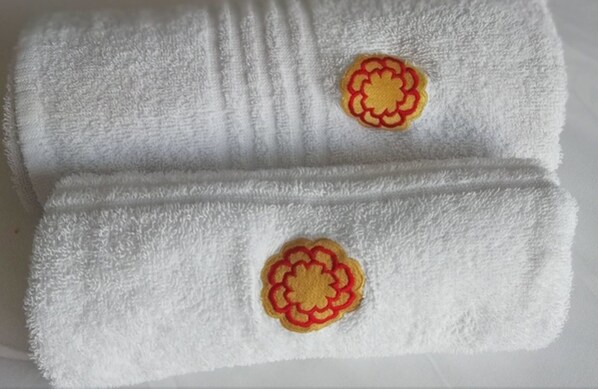 A white towel with two embroidered floral patches. - Florida Park Hotel (Durban)