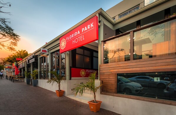 A modern hotel exterior with a prominent sign reading "Florida Park Hotel," large windows, and potted plants along the sidewalk. - Florida Park Hotel (Durban)