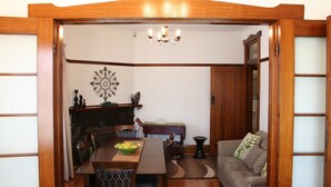 A traditional Japanese-style room with tatami flooring, a low wooden table with a bowl of fruit, a sofa with cushions, and a decorative wall piece. - Moonah Central Apartments (Moonah)