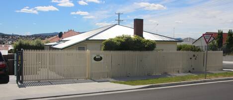 A fenced property with a metal roof, a visible chimney, and a "Give Way" traffic sign.