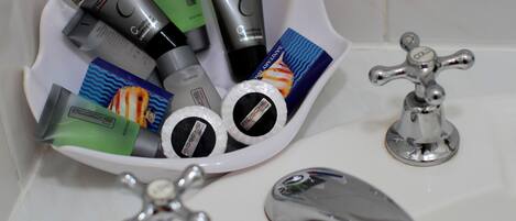 A bathroom sink with multiple toiletries and two faucets.