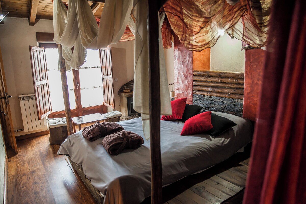 A room with a bed, a bench, and a window with curtains.