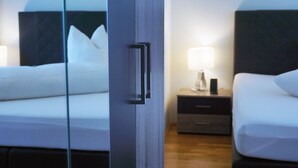 Une chambre d’hôtel avec un lit, une table de chevet avec une lampe et un miroir qui reflète la pièce.