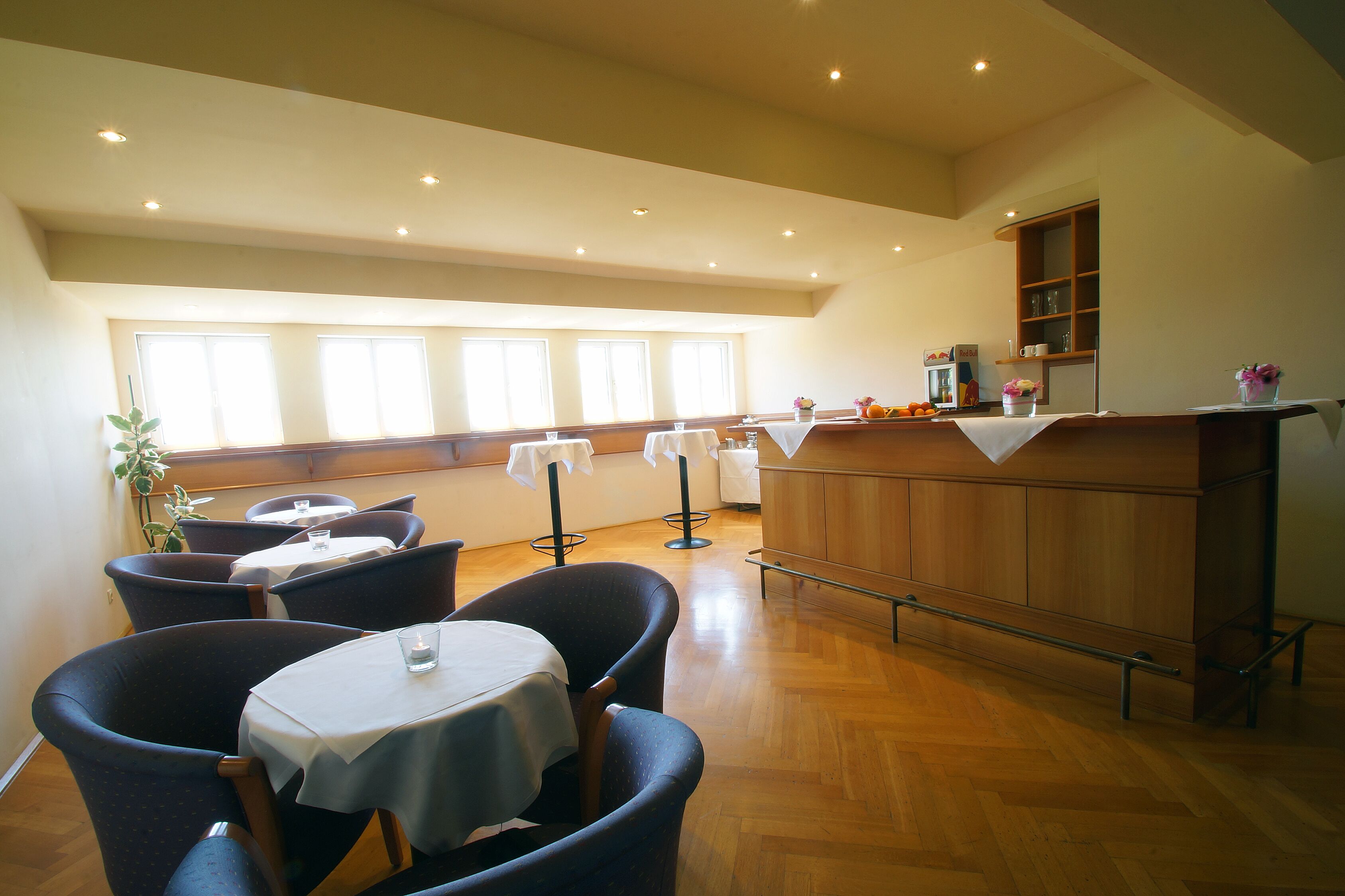 A dining area with tables and chairs, a bar area, and large windows providing natural light.