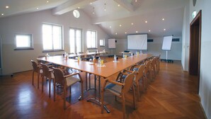 Une grande salle de conférence équipée d’une longue table, de nombreuses chaises et d’un écran de projection.