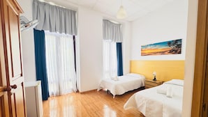 Een hotelkamer met twee bedden, een houten vloer, een plafondventilator en een schilderij van een zonsondergang.