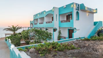 A two-story building with a turquoise and white exterior, featuring balconies and a staircase leading to the upper floor.