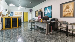 A reception area with a counter, chairs, and artwork on the walls. - Alpha Studios (Karpathos)