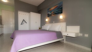 A bedroom with a bed, nightstands, a wardrobe, and a painting on the wall. - Alpha Studios (Karpathos)