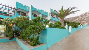 A building with turquoise walls and a stone pathway leading to the entrance. - Alpha Studios (Karpathos)