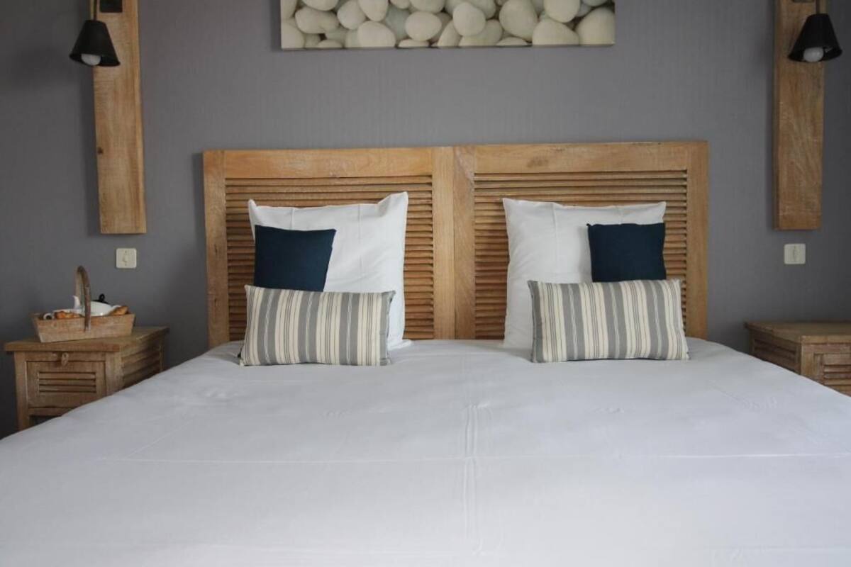 A double bed with a wooden headboard, two pillows, and a bedside table with a basket.