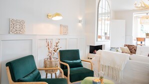A modern living room with a fireplace, two green armchairs, a white sofa, and decorative wall art. - Casa Julia (Delft)