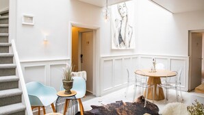 A modern interior with a staircase, a dining area with a round table and chairs, and a large abstract painting on the wall. - Casa Julia (Delft)