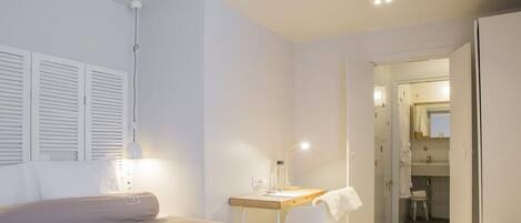 A bedroom with a bed, a desk, and a bathroom visible through an open door.