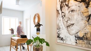 A modern interior with a laptop on a wooden chair, a large abstract painting, and potted plants. - Casa Julia (Delft)