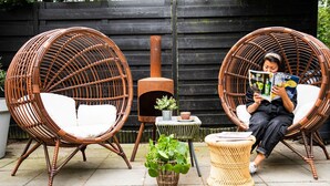 Two wicker chairs with cushions, a small table with a plant, and a person reading a magazine. - Casa Julia (Delft)