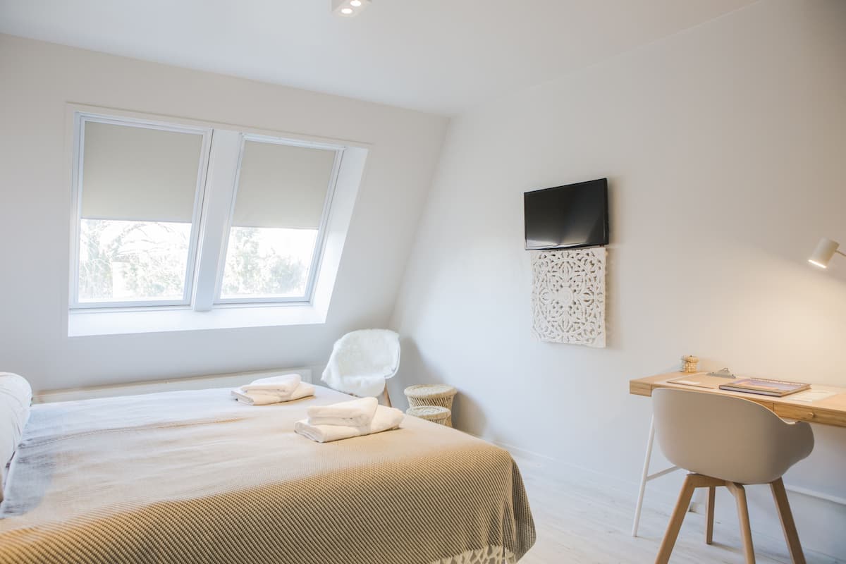 Un dormitorio con cama, escritorio y silla.