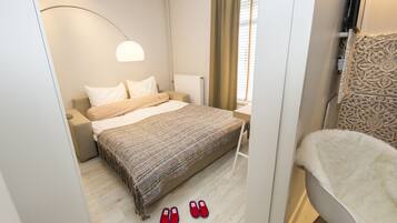 Habitación de hotel con cama, mesita de noche, lámpara, ventana con cortinas y una silla.