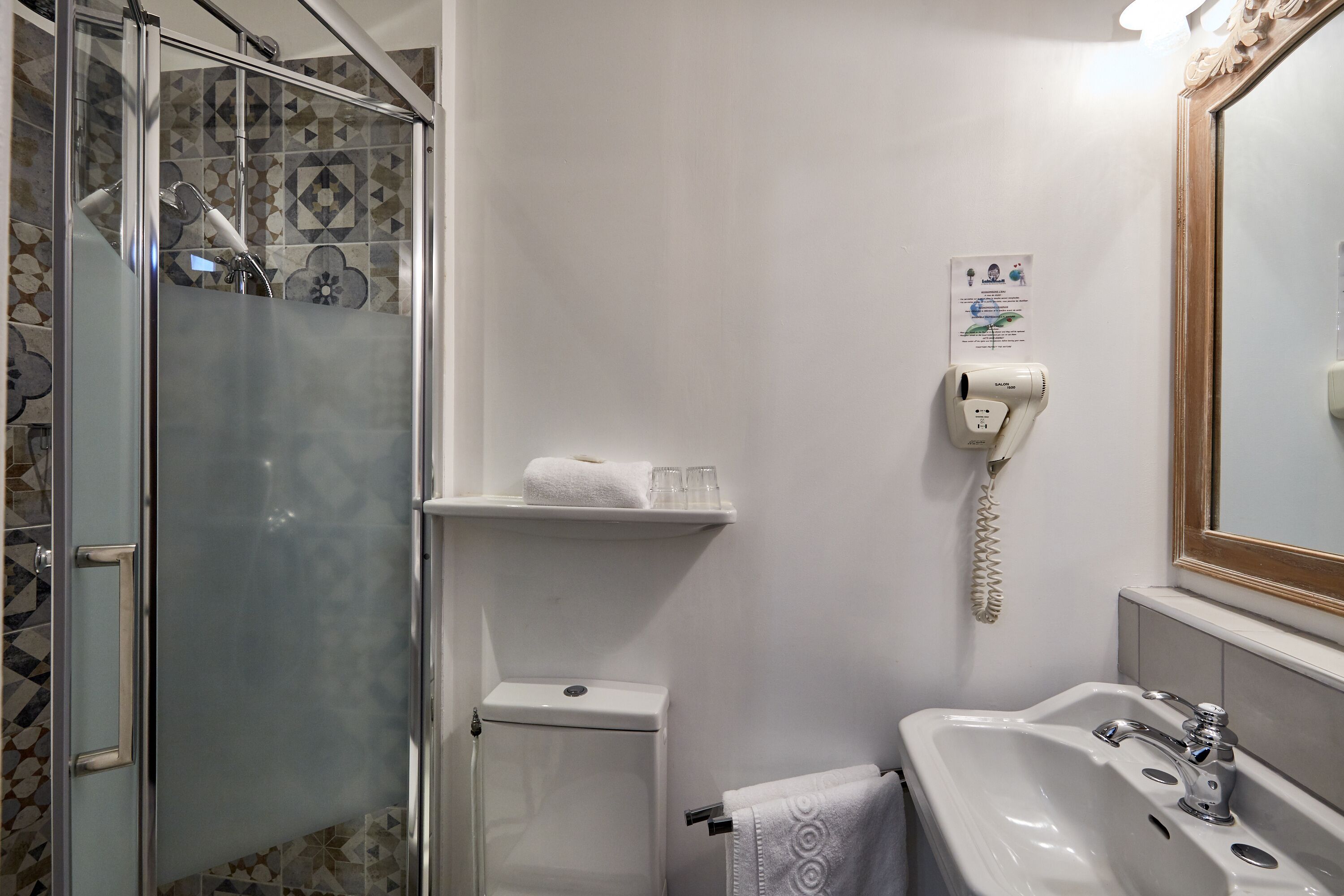 A bathroom with a glass shower enclosure, a toilet, a sink, and a mirror.