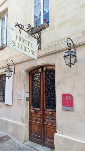 A hotel entrance with a sign reading "HOTEL SÉTIENNE," ornate ironwork on the door, and a red "H" sign on the wall. - Hôtel Saint Etienne (Caen)