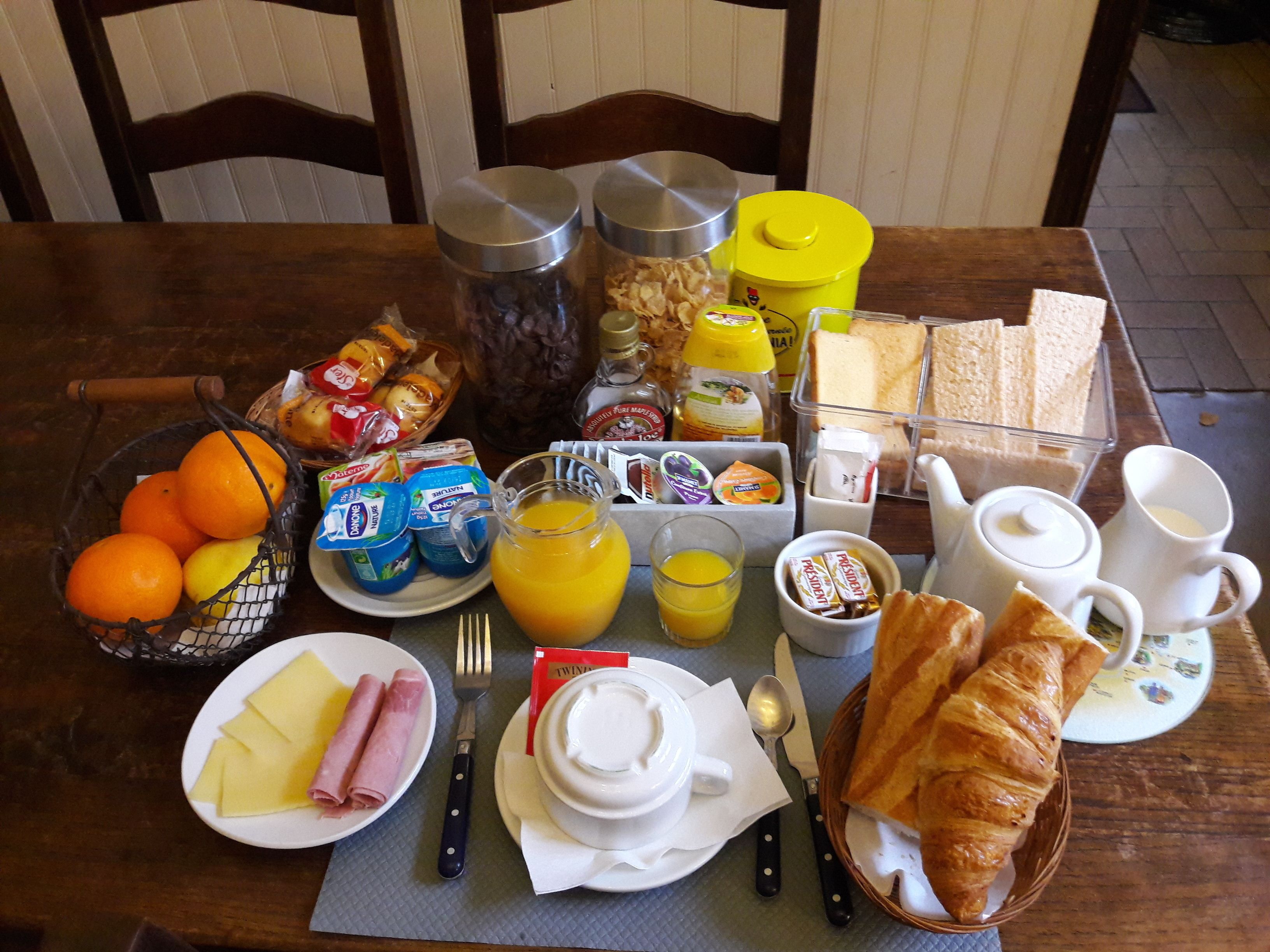 Une table de petit-déjeuner avec divers aliments, notamment du pain, des œufs et des fruits.