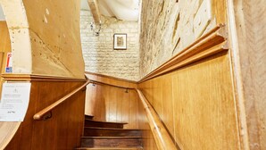 Una escalera de madera con un muro de piedra y un cuadro enmarcado en la pared.