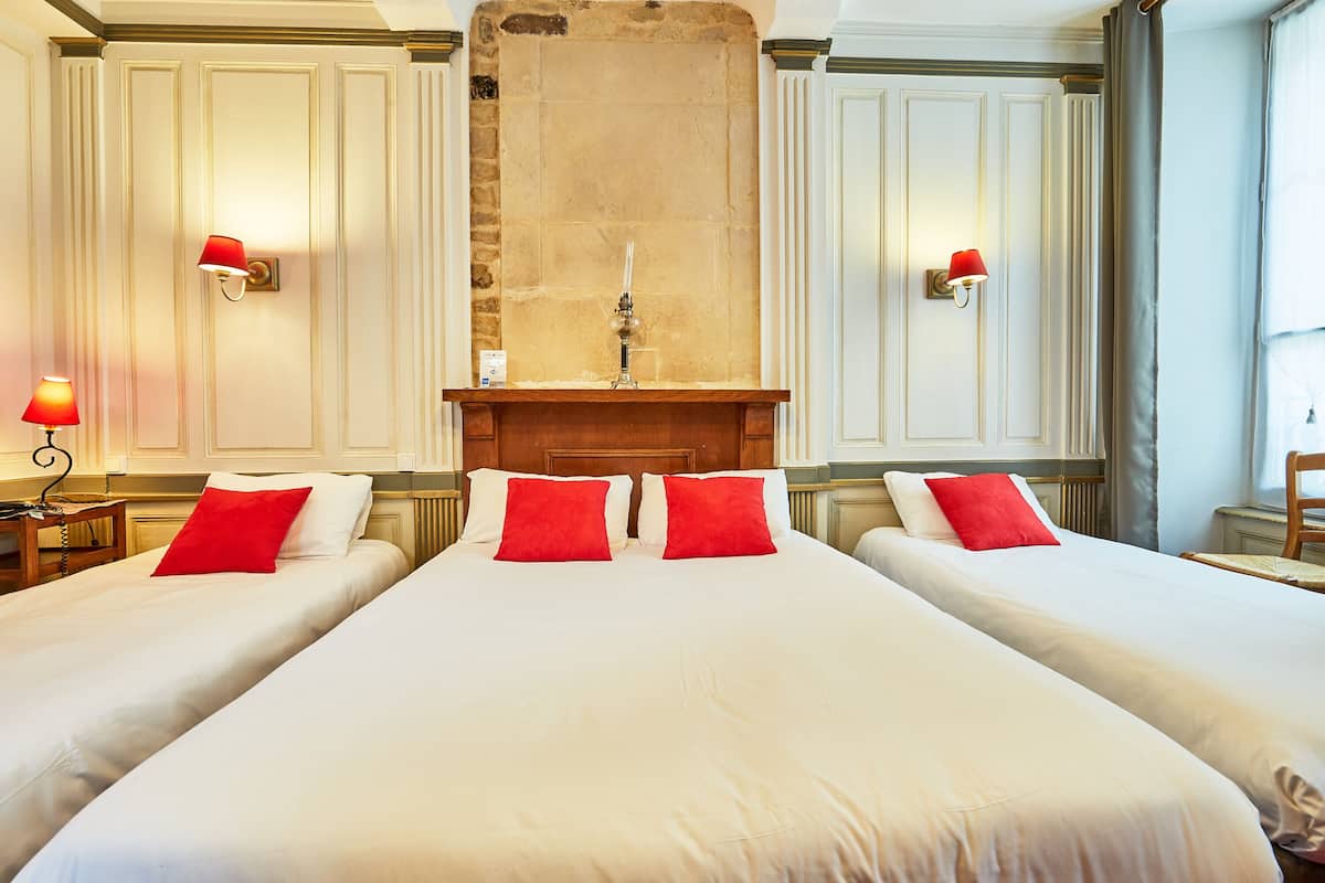 A hotel room with two beds, a stone fireplace, and wall sconces.