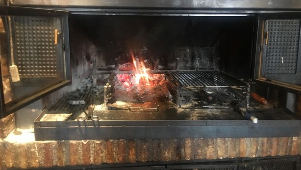 An open oven with visible flames and a metal grate. - Hostal Jaime I (Huesca)