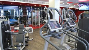 A gym with various exercise machines, a large screen, and a red floor. - City Gardens Apartments (Budapest)