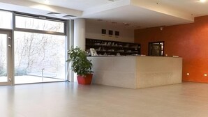 A spacious lobby with a reception desk, large windows, and a potted plant. - City Gardens Apartments (Budapest)