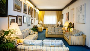 A living room with sofas, a coffee table, and a lamp. - Hotel Sabrina (Castiglione della Pescaia)