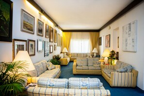 A living room with sofas, a coffee table, and a lamp. - Hotel Sabrina (Castiglione della Pescaia)