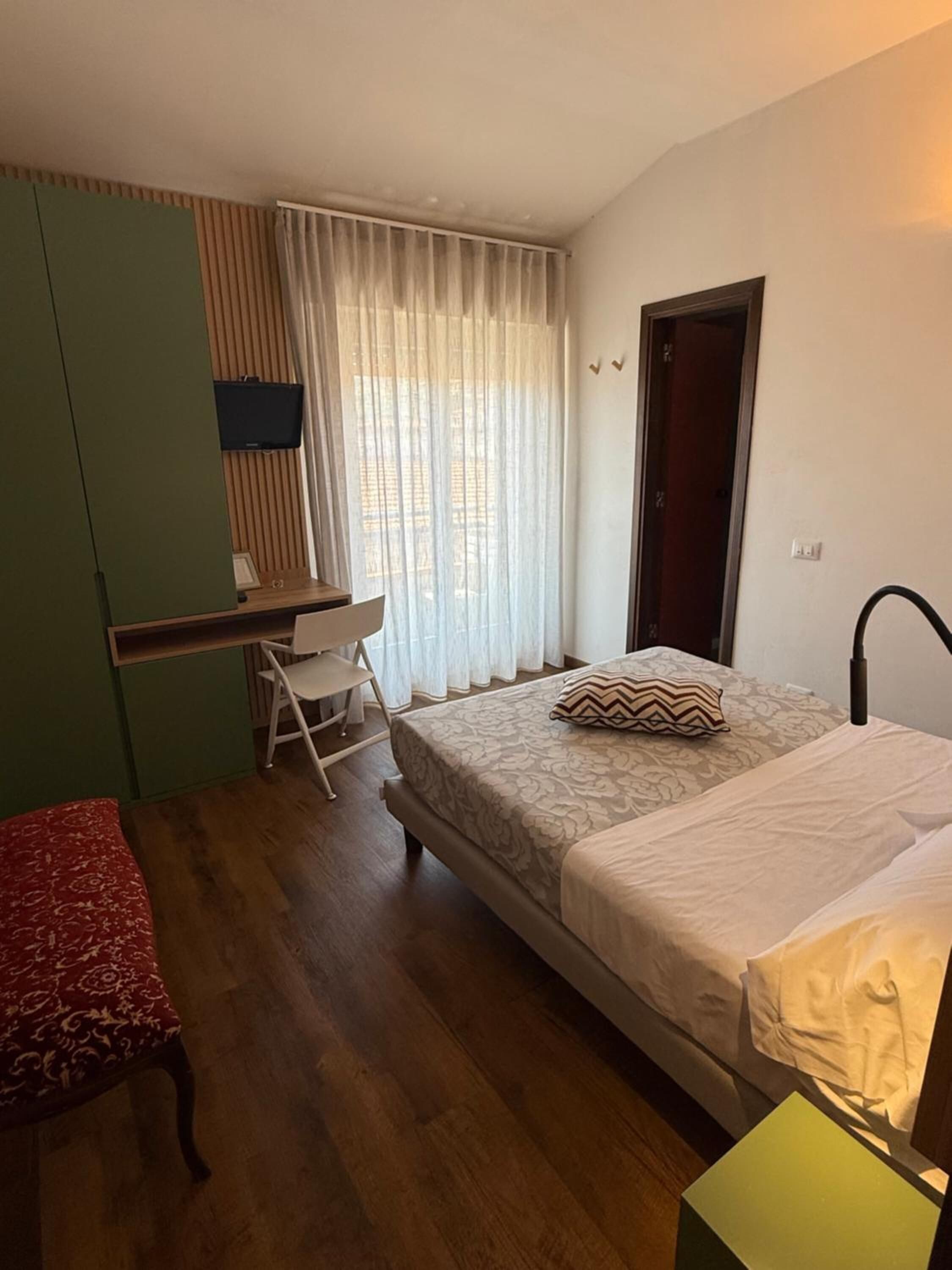 Een kamer met een bed, een bureau, een stoel, een bank en een deur.
