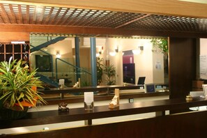 Un comptoir d’accueil avec un miroir, un escalier et une plante en pot.