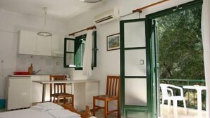 A compact bedroom with a bed, a desk, and a chair, a small kitchenette, and a balcony with a view of trees. - Harmony Resort (Parga)