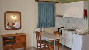A compact kitchen with a dining table, chairs, a small sink, and a mirror. - Harmony Resort (Parga)