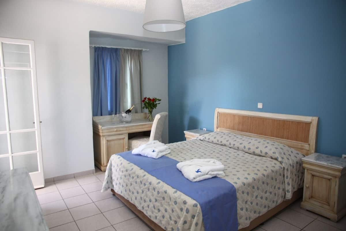 Um quarto com uma cama, uma escrivaninha, uma cadeira e uma mesa de cabeceira.