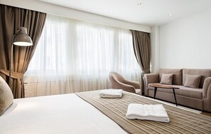 Una habitación de hotel con cama, sofá, una mesita y una lámpara.