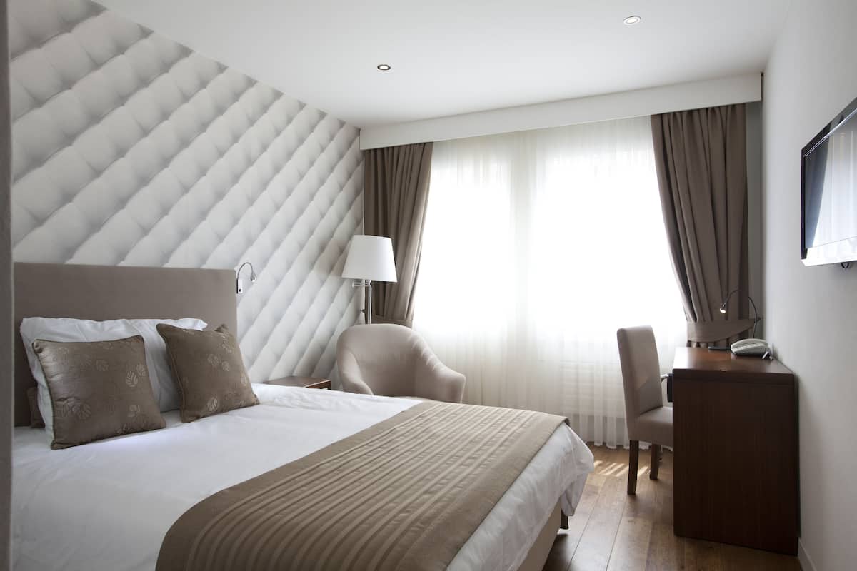 Quarto de hotel moderno com uma cama grande, uma escrivaninha e uma cadeira.