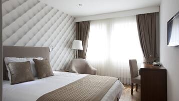 Ein modernes Hotelzimmer mit einem großen Bett, einem Schreibtisch und einem Sessel.