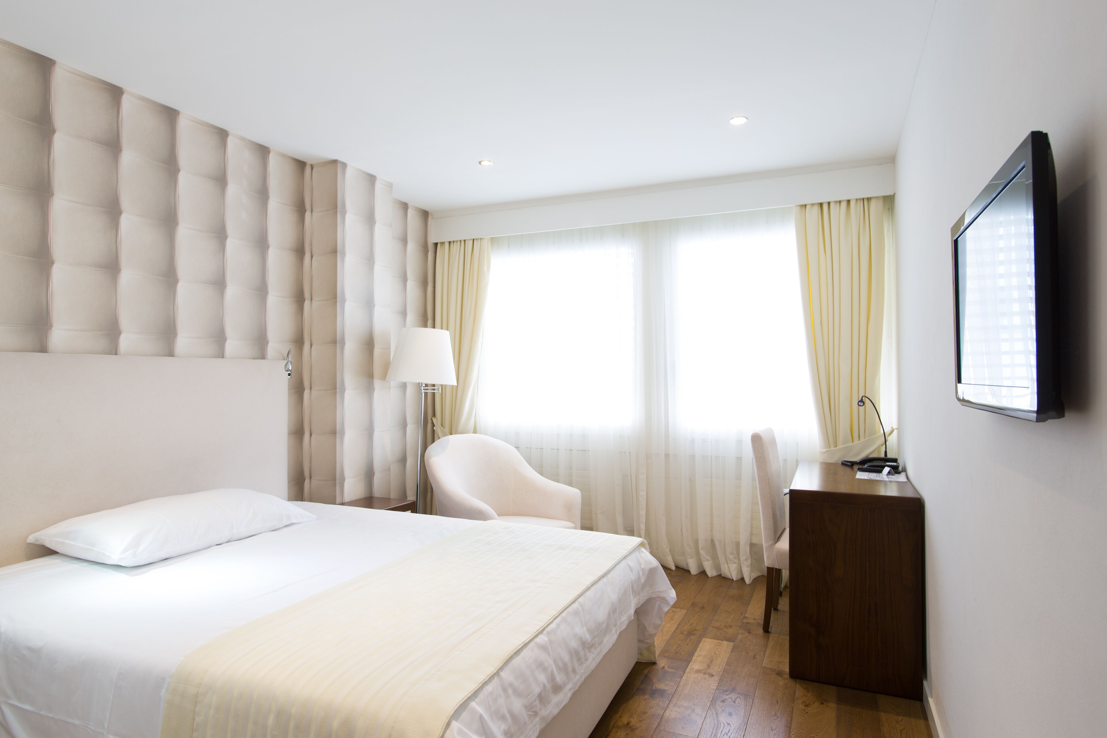 A hotel room with a large bed, a desk, and a chair.