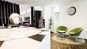 A reception area with a globe, a chalkboard with text, and two green chairs. - Hotel Alpha (Fribourg)