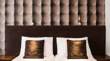 Uma cama de casal com duas almofadas, cabeceira escura e parede com painel trabalhado.