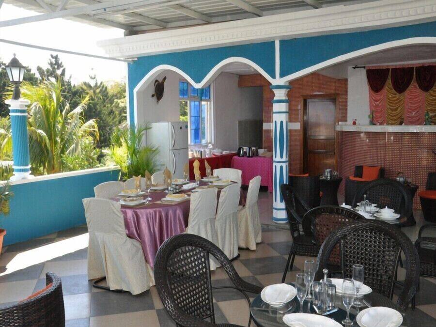 A restaurant with outdoor seating, white chairs, and tables set for dining.